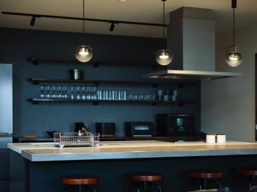 a kitchen with a bar with bar stools and lights at Private villa FujiNagi in Oishi