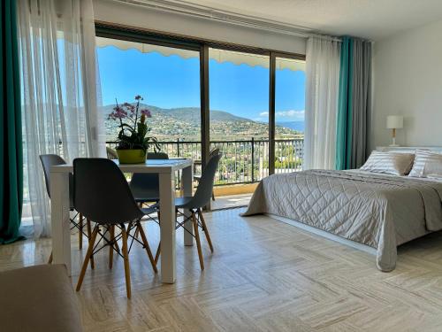 une chambre avec un lit, une table et des chaises dans l'établissement My Resid Appart Cannes vue marina et vue montagne, à Mandelieu-la-Napoule
