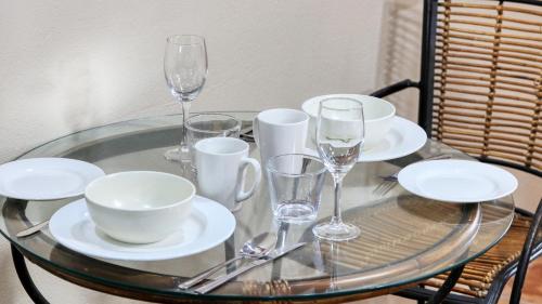 a glass table with plates and wine glasses on it at Mackay Rose Motel in Mackay