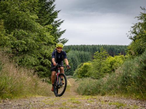 a man riding a bike down a dirt road at 3-bedroom house for outdoor holidays in Alyth