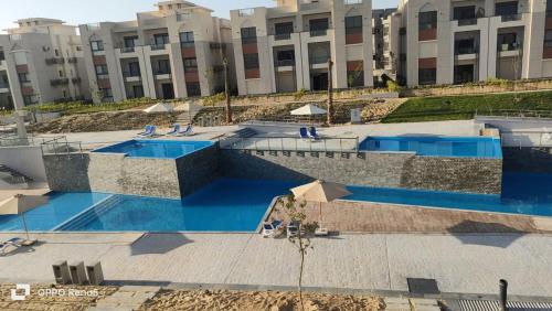 a swimming pool in front of a large building at Mohamed Afifi GAIA Ras El-Hekma - Penthouse 2BR- Families Only in Ras Elhekma