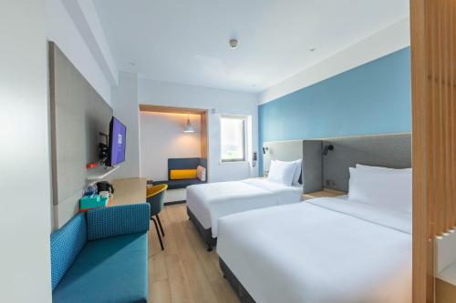 a hotel room with two beds and a chair at Holiday Inn Express Shanghai Pudong Airport by IHG in Shanghai