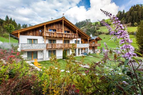 a house on a hill with flowers in the foreground at Alpine Mountain Chalet in San Vigilio Di Marebbe