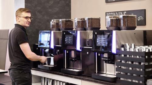 a man is standing in front of a coffee machine at Holiday Inn - the niu, Air Frankfurt Messe by IHG in Frankfurt/Main