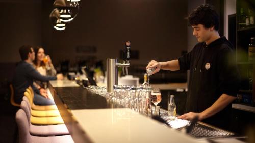 a man standing at a bar preparing wine glasses at Holiday Inn - the niu, Air Frankfurt Messe by IHG in Frankfurt/Main