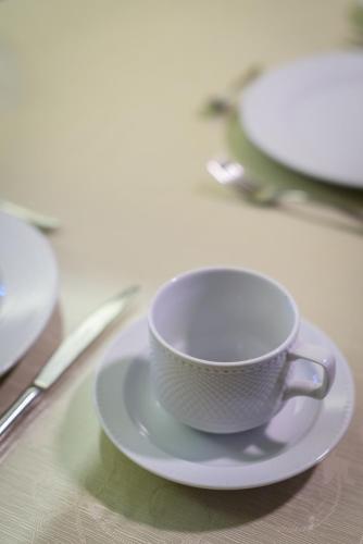 a white cup on a plate on a table at Ionion Beach Apartment Hotel & Spa in Arkoudi