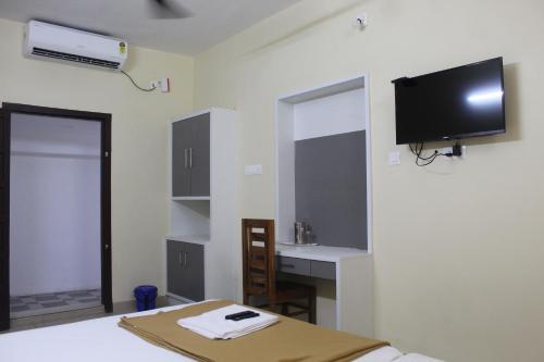 a bedroom with a bed and a tv on the wall at Anna Hotel in Trivandrum