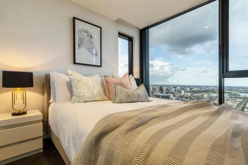 a bedroom with a bed with a large window at Sophisticated Designer Condo w City & Bay Views in Melbourne