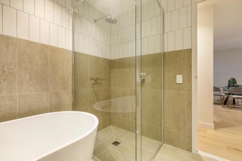 a bathroom with a tub and a glass shower at Sophisticated Designer Condo w City & Bay Views in Melbourne