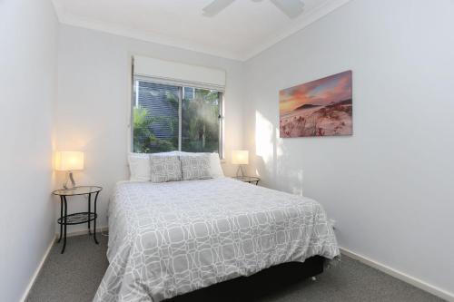 a white bedroom with a bed and a window at Lovely Pet Friendly Beach House in Hawks Nest