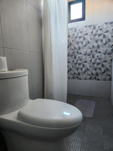 a white bathroom with a toilet and a shower at Casa Vacacional Amaia in Mazatlán