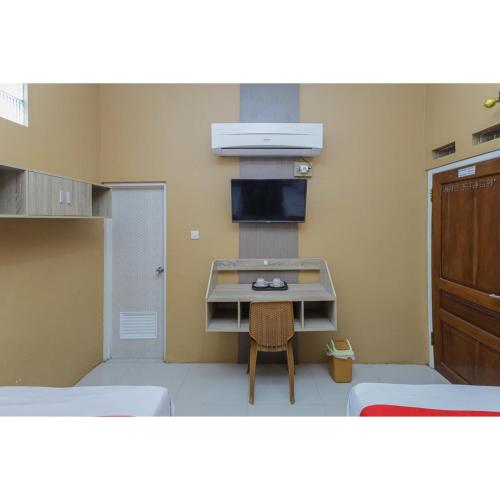a small room with two beds and a table in it at Reddoorz Syariah at House Of Melati Kepanjen in Malang