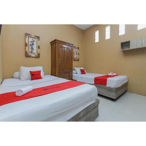 a bedroom with two beds with red and white sheets at Reddoorz Syariah at House Of Melati Kepanjen in Malang