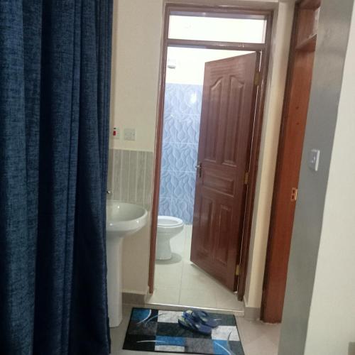a bathroom with a toilet and a wooden door at Wolf Cabins 2 in Nyeri