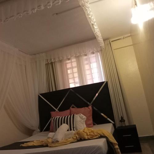 a bedroom with a bed with a black headboard and a window at Wolf Cabins 2 in Nyeri