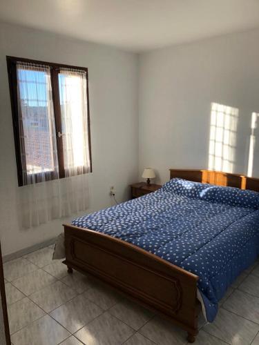 - une chambre avec un lit avec une couette bleue et 2 fenêtres dans l'établissement Ancien corps de ferme renove, à Tavernes