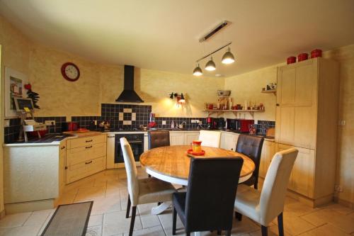 a kitchen with a wooden table and chairs in it at L'etable des saveurs in Cieux