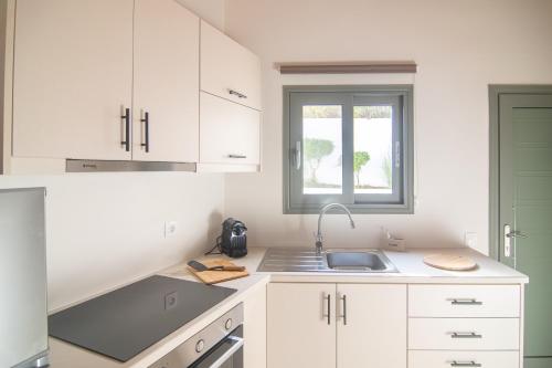 a kitchen with white cabinets and a sink at Cygnus - Summertime Stars in Afionas