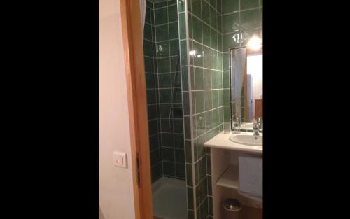 La salle de bains est pourvue d'une douche carrelée de couleur verte et d'un lavabo. dans l'établissement La cigale rouge a callian, à Callian