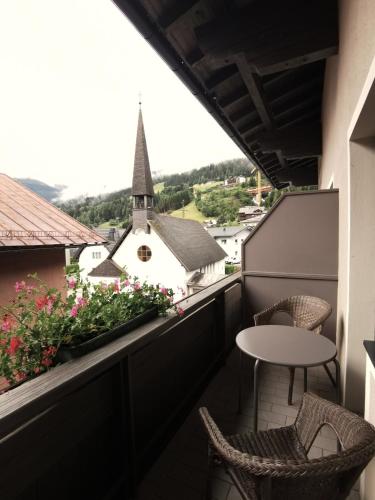 a balcony with a table and chairs and a church at Schlossalm Appartement in Bad Hofgastein