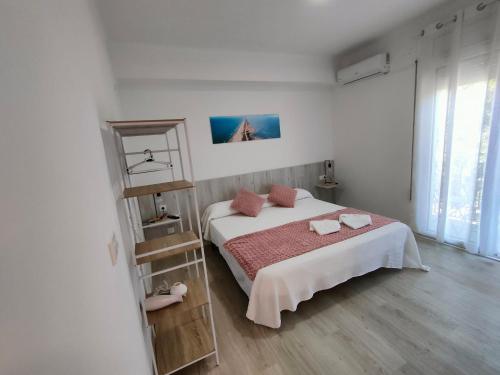 a white bedroom with a bed and a large window at Bahía de Montecarlo in Alcanar