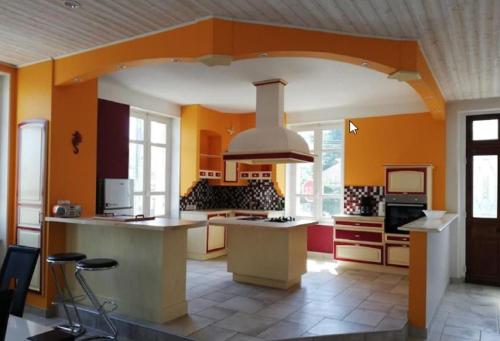 - une grande cuisine avec des murs orange et une cuisinière four supérieur dans l'établissement Maison de 100m2 au cœur d'une pension équestre Les Sabots de Nina, à Marcollin