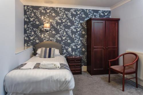 a bedroom with a bed and a chair and a wall at The Babbacombe Hotel in Torquay