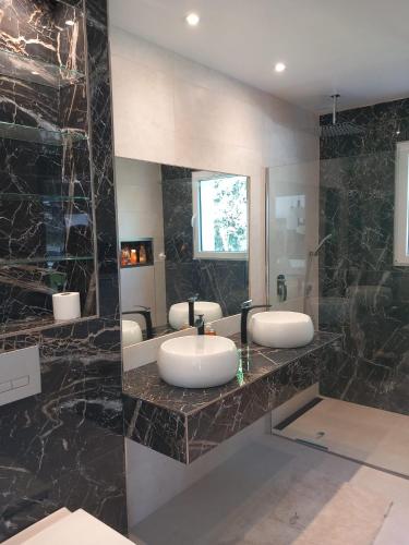 La salle de bains est pourvue de 3 lavabos et d'un grand miroir. dans l'établissement Villa Victoria, à Marennes