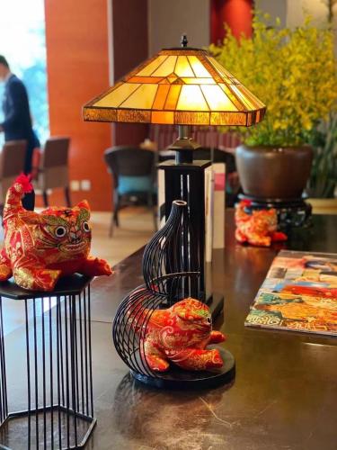 a table with a lamp and a vase with chickens on it at City Hotel Xiamen-Free Welcome Fruits in Xiamen
