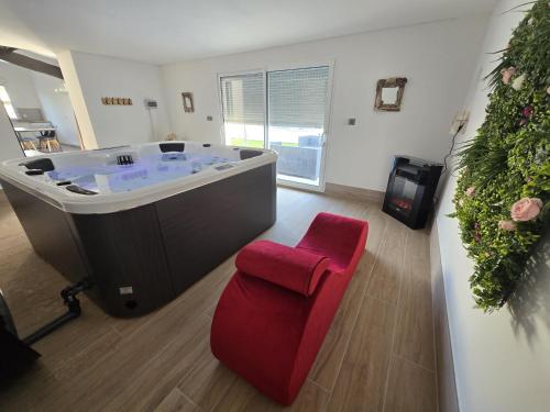 La grande salle de bains est pourvue d'une baignoire et d'un fauteuil rouge. dans l'établissement Evasion de charme, à Saint-Marcel-dʼArdèche