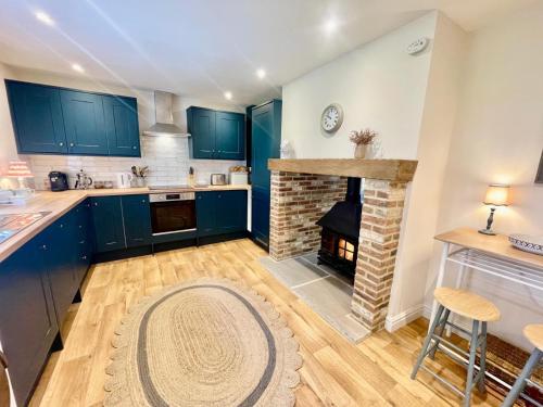 a kitchen with blue cabinets and a brick fireplace at Moat Cottage, Newby Hall, Ripon, North Yorkshire in Copt Hewick