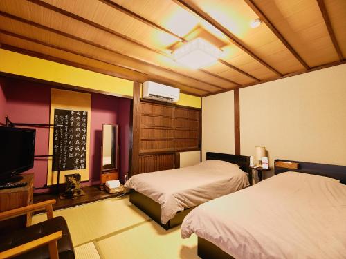 a bedroom with two beds and a tv in it at 以久波別邸虎屋 in Ukiha