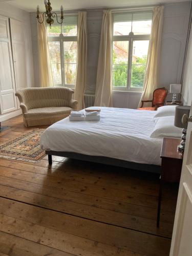 Un dormitorio con una cama y una silla y ventanas. en Maison Monsigny, en Saint-Omer