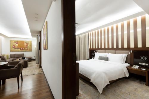a bedroom with a bed and a living room at Babylon Rotana Hotel in Baghdad