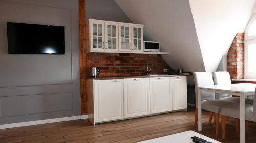 a kitchen with white cabinets and a tv on a wall at Vintageapartment in Sopot