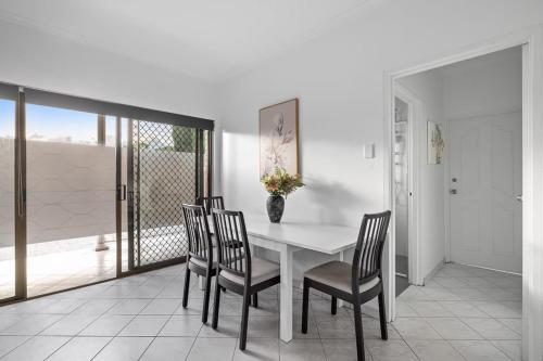 a dining room with a white table and chairs at Cozy Private Double Room - Near Stations & Shops - Shared Bathroom in Bankstown