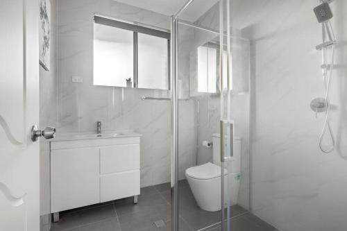 a bathroom with a toilet and a glass shower at Cozy Private Double Room - Near Stations & Shops - Shared Bathroom in Bankstown