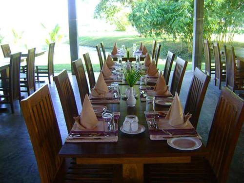 a long wooden table with napkins on top of it at Thompukandam Village Resort in Nintavur