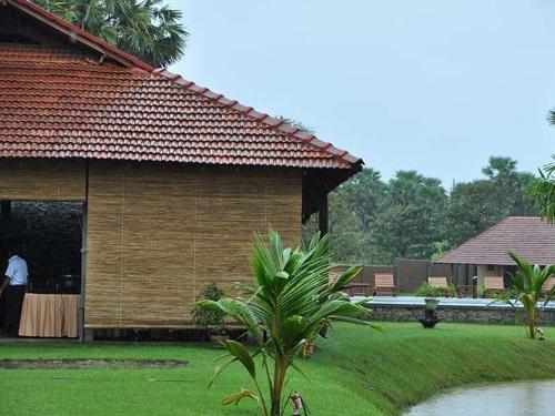 a man standing outside of a building with a table at Thompukandam Village Resort in Nintavur