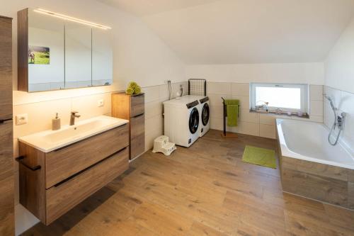 y baño con bañera, lavabo y lavadora. en Ferienwohnung Egg-Hof, en Bad Grönenbach