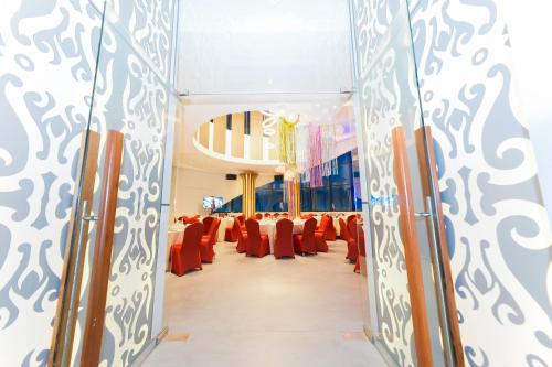 a hall with red chairs and tables in a room at The All - Suite Pentacity Hotel Balikpapan in Balikpapan