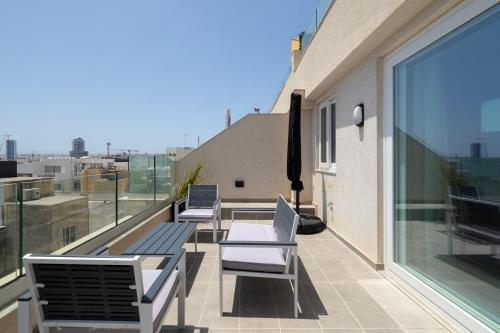 a balcony with chairs and tables on a building at Modern 2BR Cosy Apartment with Large Terrace - Close to Manoel Island & Tigne Shopping Mall in Sliema