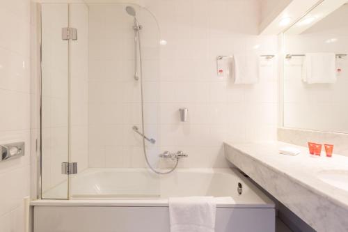 a bathroom with a shower and a tub and a sink at Leonardo Hotel Lelystad City Center in Lelystad