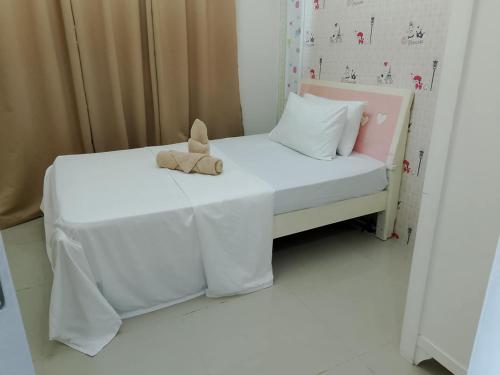 a teddy bear sitting on a bed in a room at Premiere Haven MOA Staycation in Manila