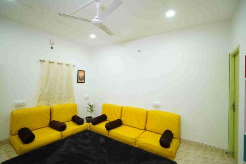 a yellow couch in a living room with a ceiling at Cayzen in Chennai