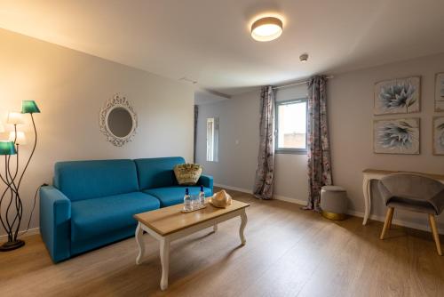 a living room with a blue couch and a table at Hôtel-Restaurant des Augustins in Saint-Cyprien