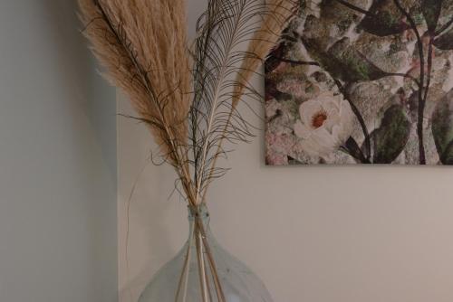 a glass vase with some dried plants in it at Hôtel-Restaurant des Augustins in Saint-Cyprien
