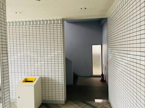 a bathroom with a white tiled wall and a hallway at ラパルフェドアンテイエール in Matsuyama