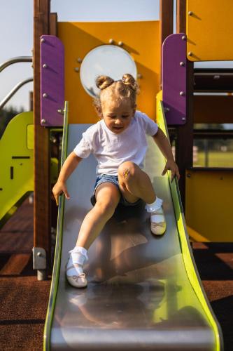a little girl riding on a slide at a playground at Apartamenty, pokoje PRZY TERMACH - 70 m Termy Szaflary, 150 m Gorący Potok in Szaflary