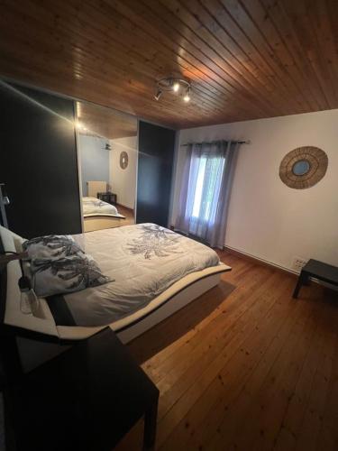 une chambre avec un grand lit et un parquet dans l'établissement Maison à la campagne avec piscine 12 pers, à Genouillé